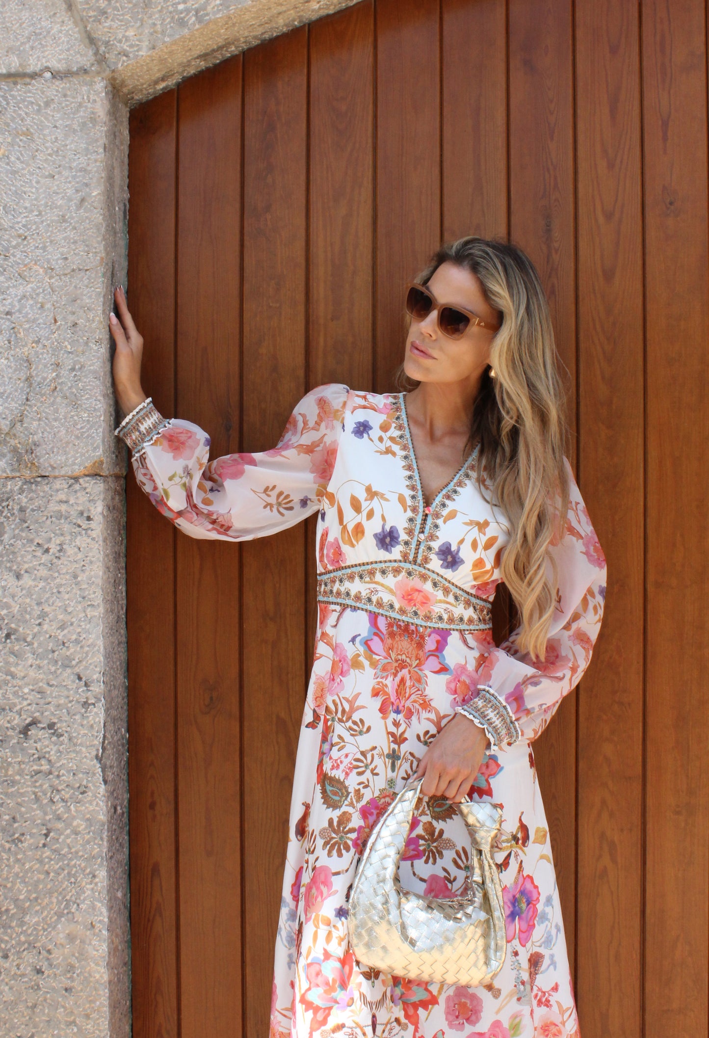Woman in a floral dress standing next to a wooden door