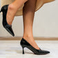 Black high-heeled shoes worn by a person sitting on a chair.