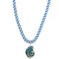Blue twisted cord necklace with a green and blue nautilus shell pendant on a white background