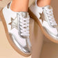 A pair of silver metallic star trainers with white laces and a 2cm sole, displayed on a light background.