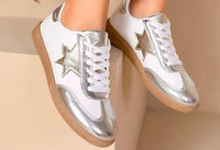 A pair of silver metallic star trainers with white laces and a 2cm sole, displayed on a light background.