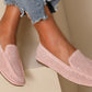 A pair of PINK laser loafer flats worn by a person sitting with crossed legs, showing the soft squared toe slip-on design with a faux suede finish.