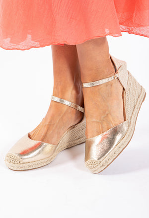 A gold espadrille style wedge sandal with a crochet look toe and an adjustable ankle strap.