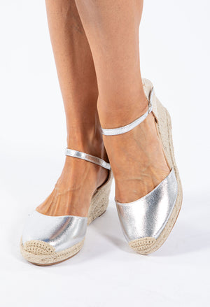 A silver espadrille style wedge sandal with a crochet look toe and an adjustable ankle strap.