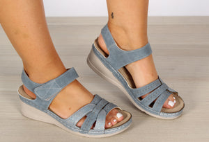 A pair of blue comfort cross strap sandals with Velcro closures, laser details, and a lightweight flexible sole.