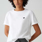 Person wearing a white t-shirt with a black heart design on a plain background
