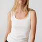 Woman wearing a white tank top against a plain background