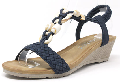 A navy-colored stone beaded wedge sandal with a braided strap and elastic ankle strap on a flat background.