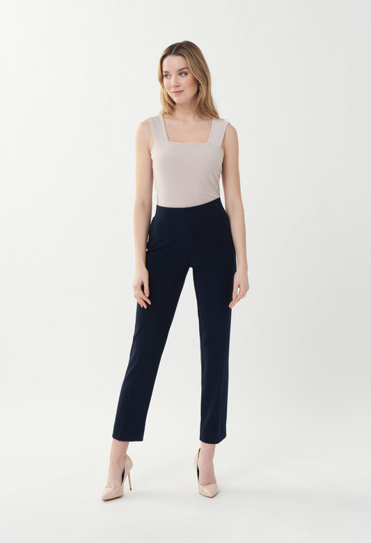 Woman wearing a white sleeveless top and black pants on a white background