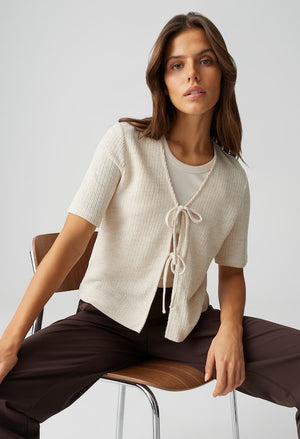 Woman wearing a cream-colored cardigan with a white background