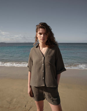 Woman standing on a beach wearing a brown outfit