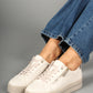 White sneakers worn with blue jeans on a gray background
