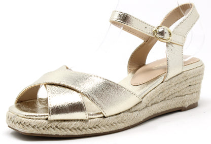 A metallic gold espadrille sandal with adjustable ankle strap and cross straps at the toe, featuring a wedge heel.