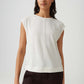 Woman wearing a white sleeveless top and dark pants on a light gray background