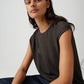 Woman wearing a dark green sleeveless top against a light gray background
