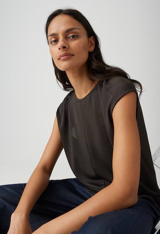 Woman wearing a dark green sleeveless top against a light gray background