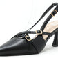 Black high-heeled slingback shoe with gold buckles on a white background
