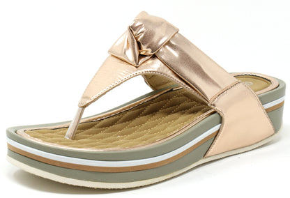 A rose gold colored sandal with a thong style strap and a flat sole.