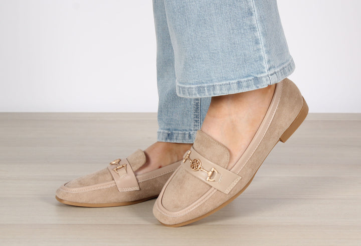 A person wearing blue faux suede loafers with leather look trims and antique gold hardware, the shoes are a slip-on style.