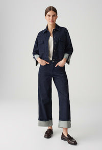 Person wearing a dark denim outfit with a white background