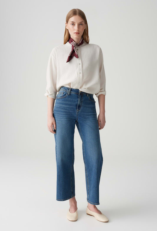 Woman wearing a white blouse and blue jeans with a red scarf on a white background