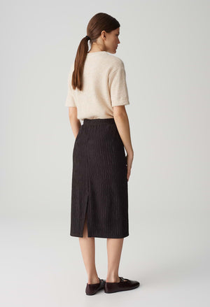 Woman wearing a beige sweater and black pinstripe skirt on a white background