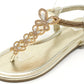 Gold sandal with decorative straps on a white background