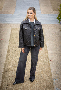 Woman wearing a black jacket and dark pants on a sidewalk.