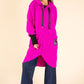 Person wearing a bright pink hooded coat on a beige background