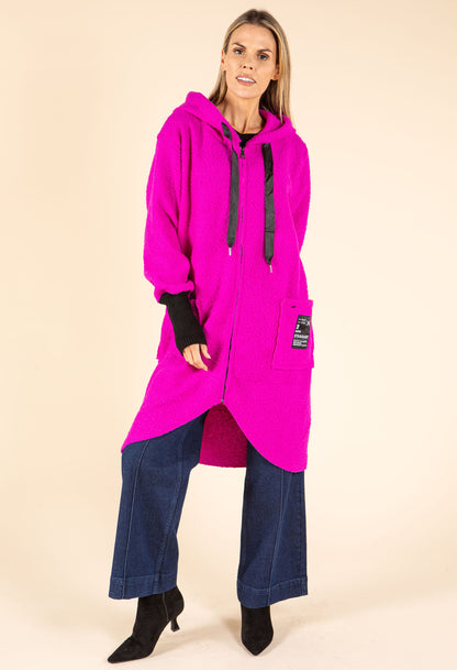 Person wearing a bright pink hooded coat on a beige background