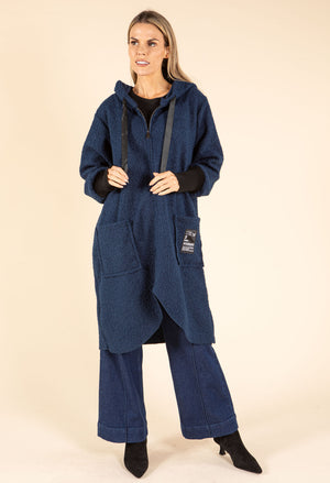 Woman wearing a blue hooded coat with a beige background