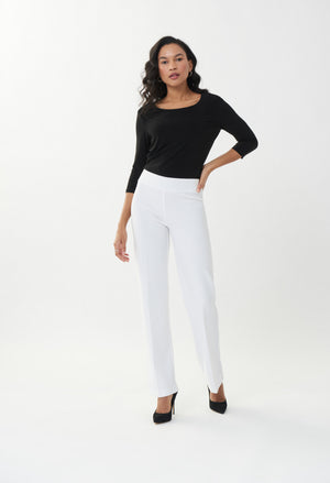 Woman wearing a black top and white pants on a white background