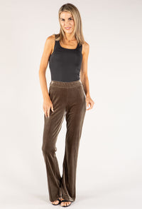 Woman wearing brown velvet pants and a black top on a white background