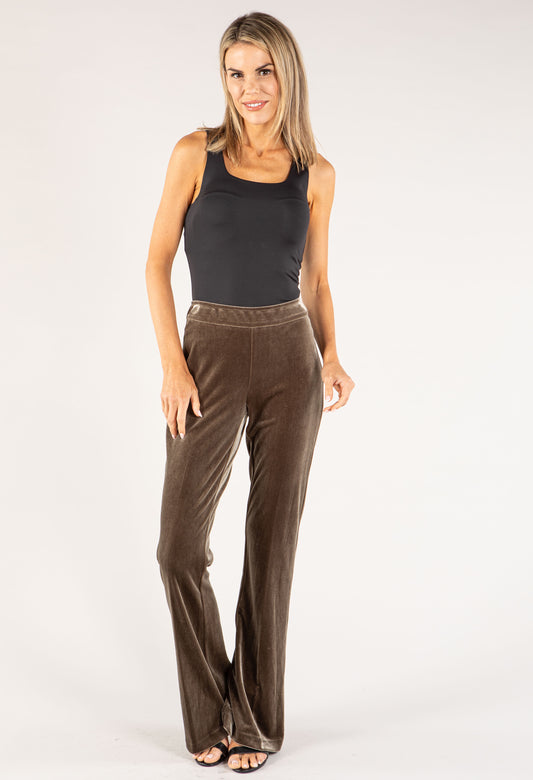Woman wearing brown velvet pants and a black top on a white background