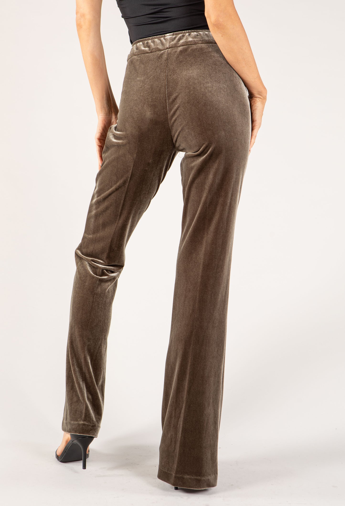Brown velvet pants worn by a person on a white background