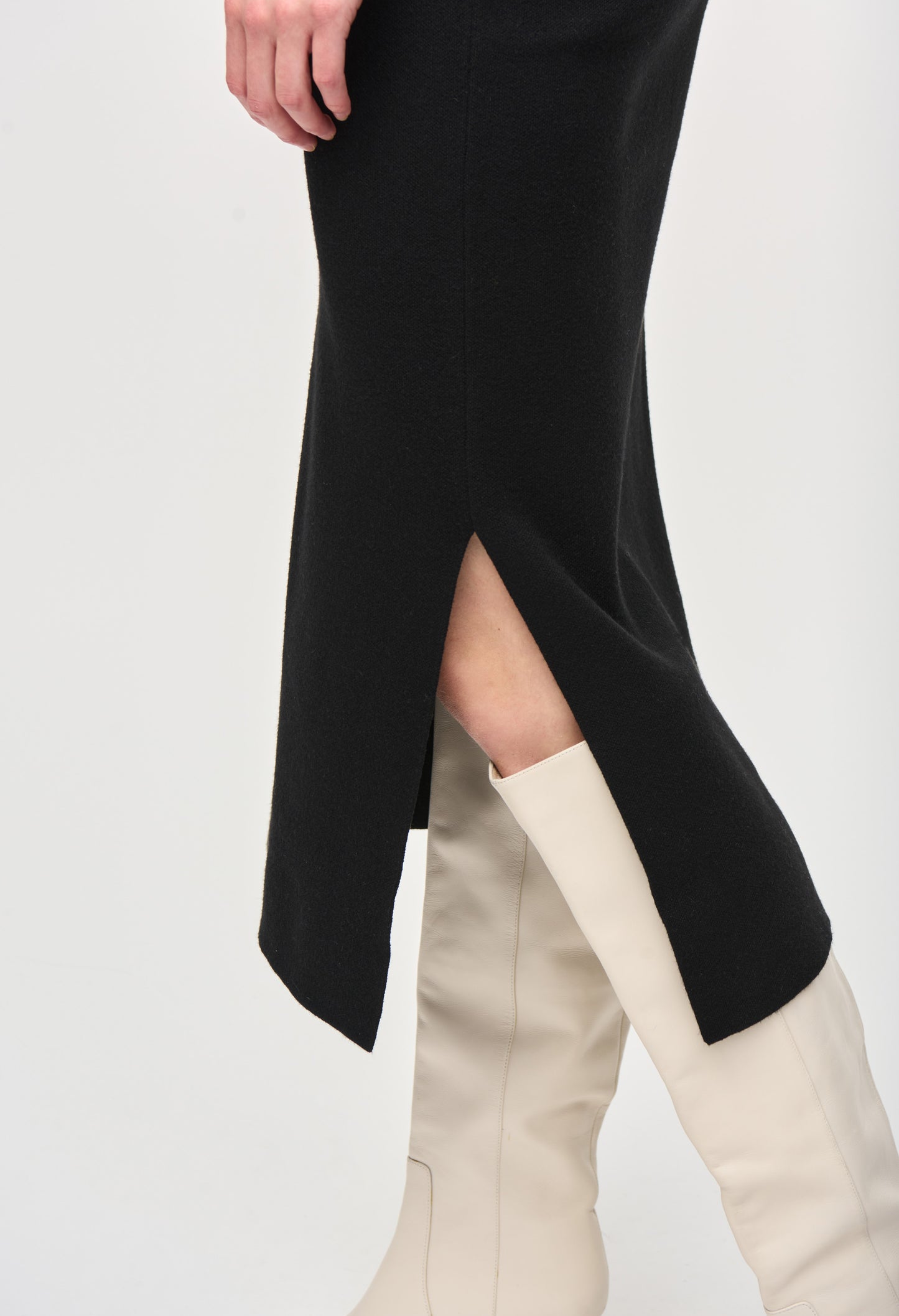 Black long-sleeve top with a high slit and beige knee-high boots on a white background