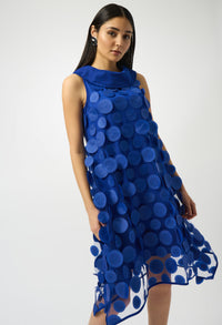 Woman wearing a blue dress with circular patterns on a white background