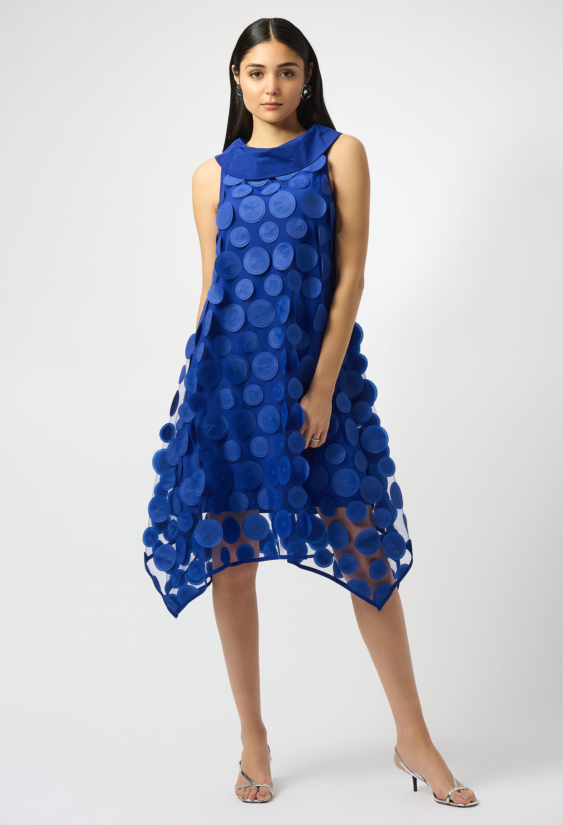 Woman wearing a blue dress with circular patterns on a white background