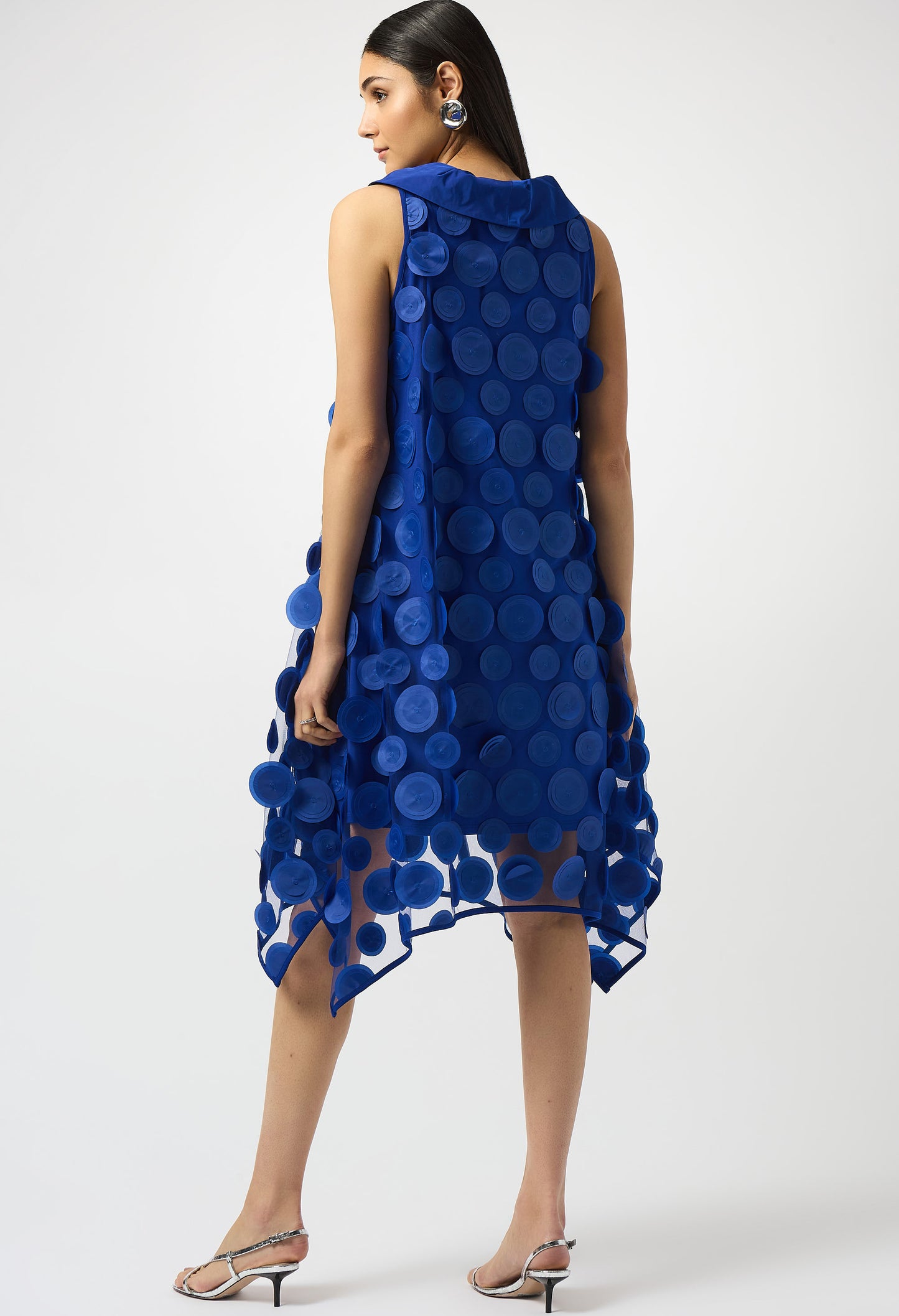 Woman wearing a blue dress with circular patterns on a white background