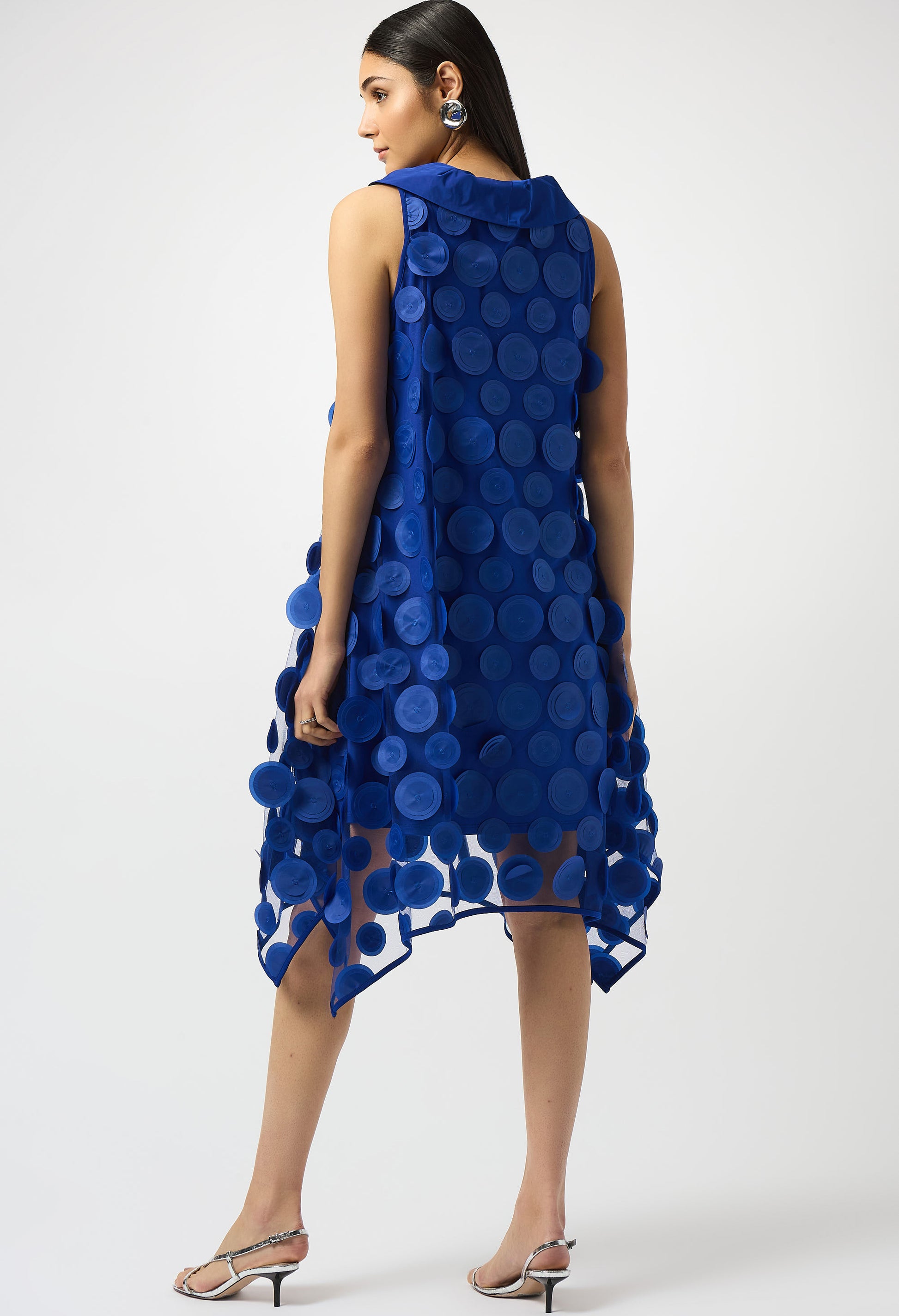 Woman wearing a blue dress with circular patterns on a white background
