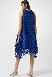 Woman wearing a blue dress with circular patterns on a white background