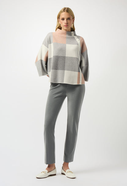 Woman wearing a checkered top and gray pants on a white background