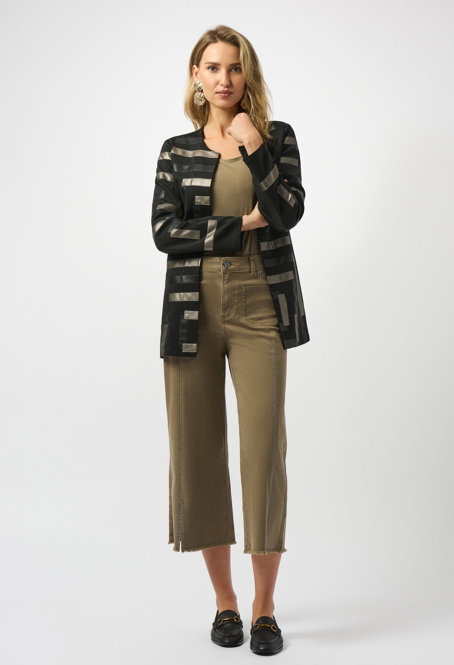 Woman wearing a black and gray patterned cardigan over a beige top and pants on a white background