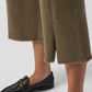 Person wearing olive green pants and black loafers on a white background