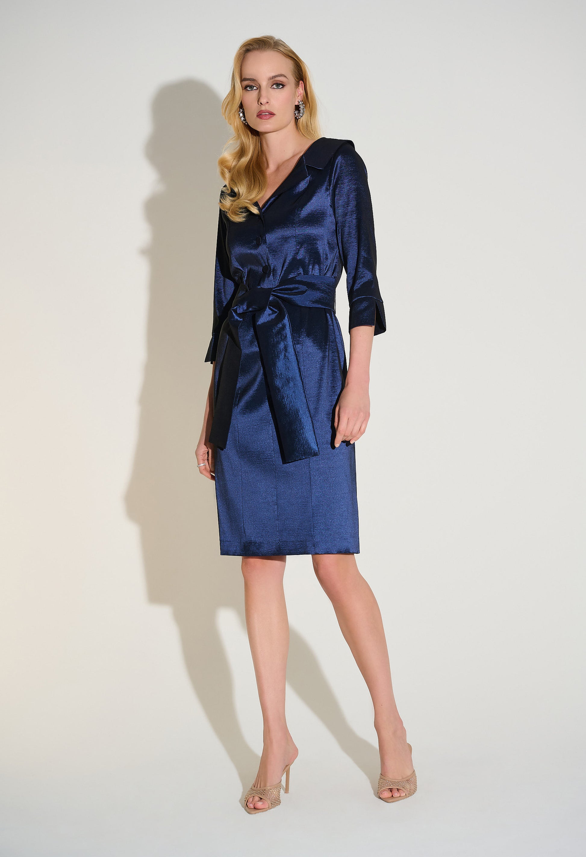 Woman wearing a blue dress with a bow detail on a white background