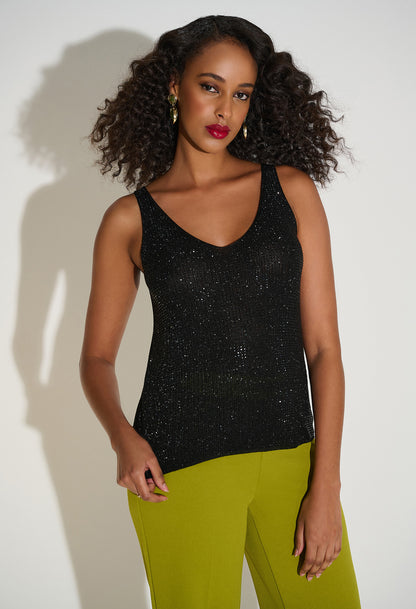 Woman wearing a black sleeveless top and green pants against a white background