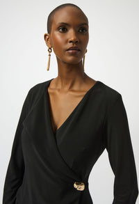 Woman wearing a black dress with a gold belt on a white background