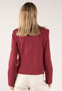 Person wearing a burgundy long-sleeve top on a white background