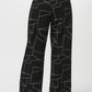 Black pants with white geometric pattern worn by a person on a white background