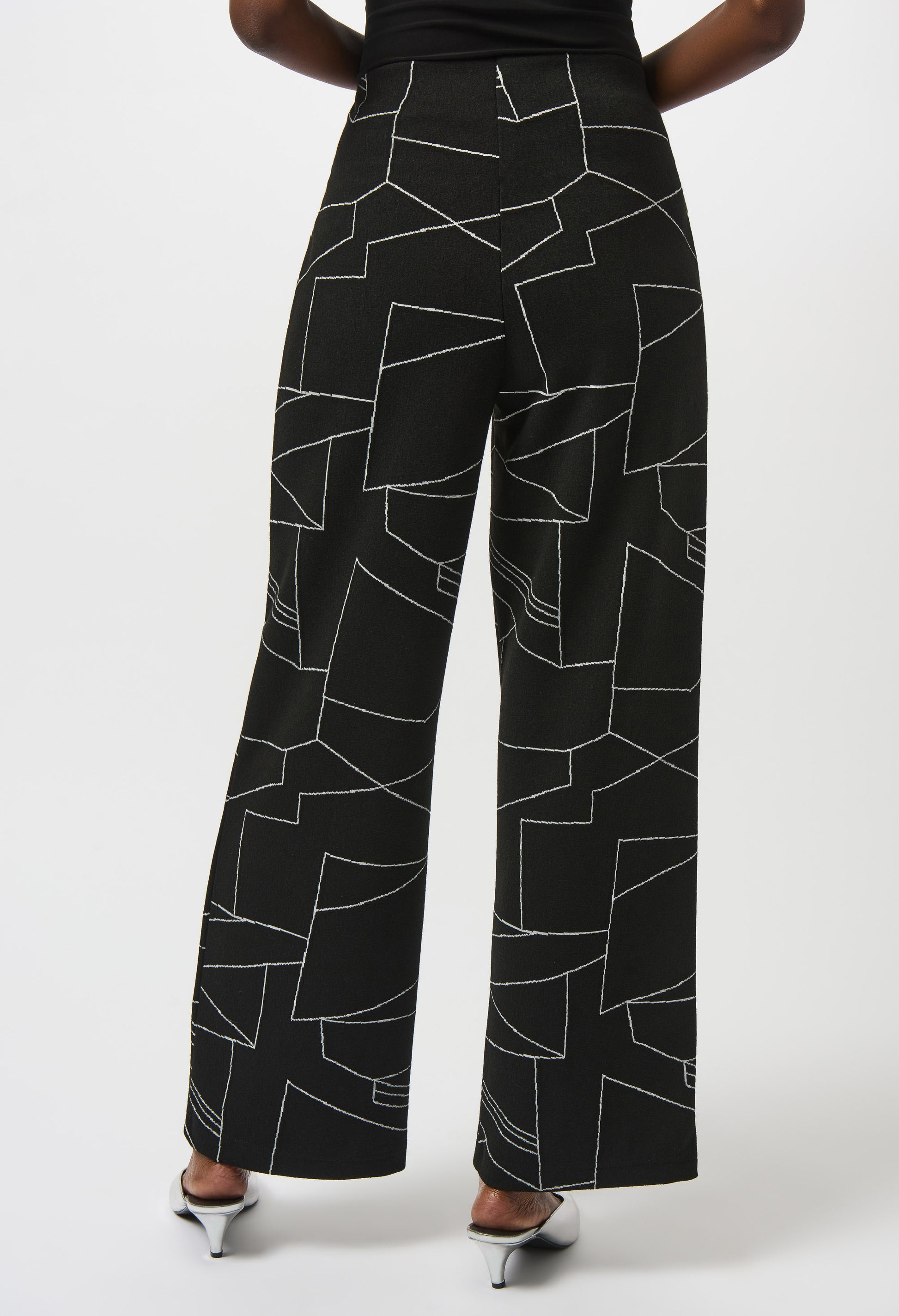Black pants with white geometric pattern worn by a person on a white background